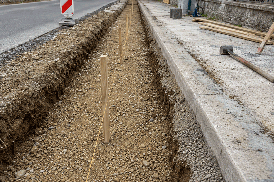 Trincea preparata e filo di tracciamento per la posa dei cordoli stradali